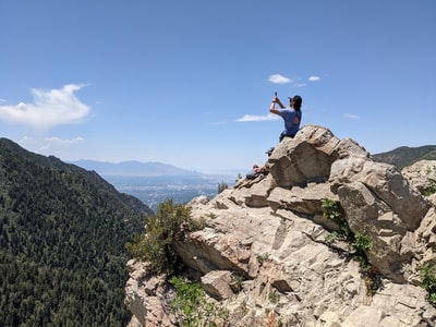 Dressed in a black shirt and blue denim jeans man jumps in the Rocky Mountains during the day
